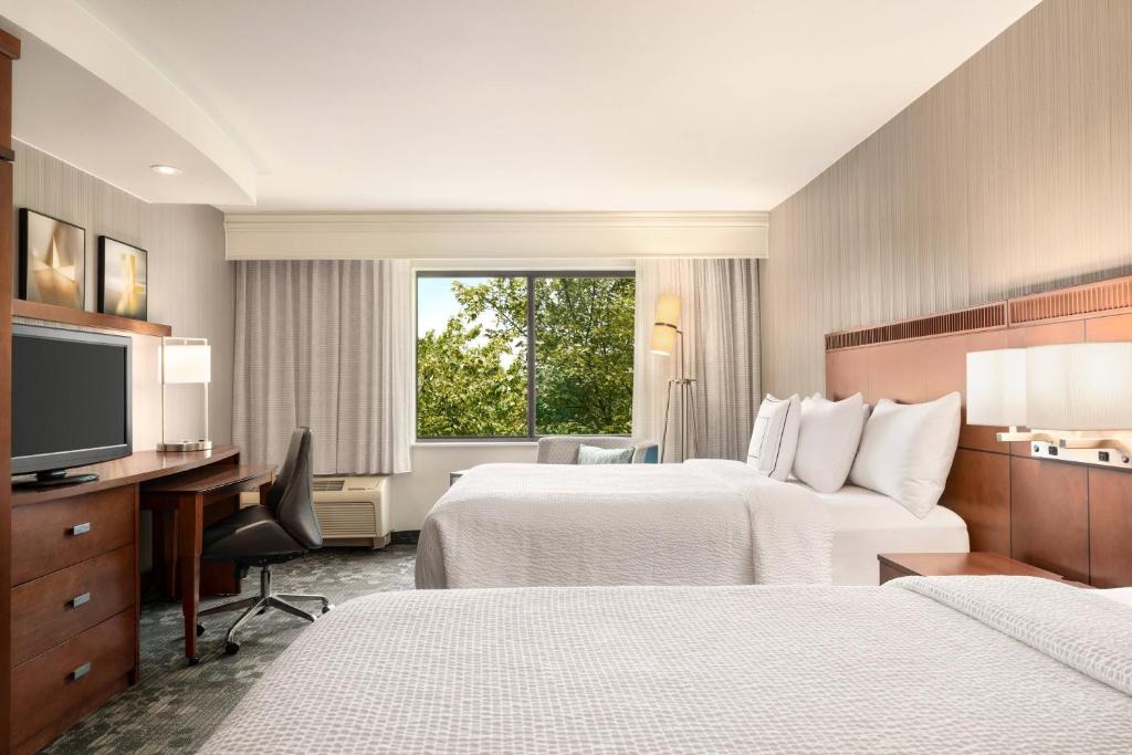 a hotel room with two beds and a desk and a television at Courtyard by Marriott Philadelphia Montgomeryville in North Wales