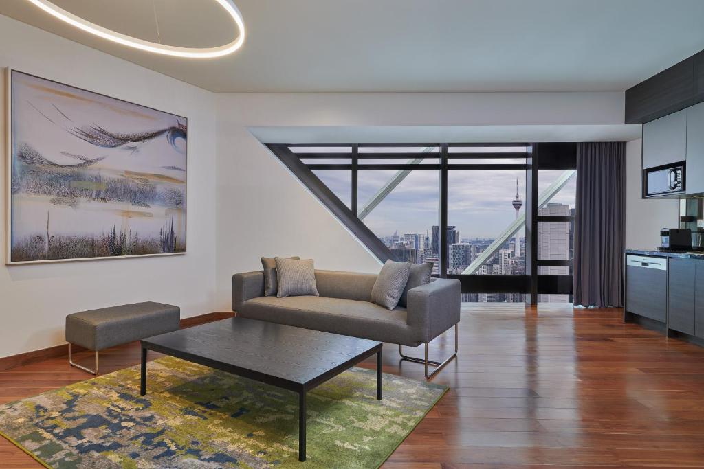 A contemporary suite living room with a sofa, coffee table, kitchen cabinetry, and tower views.