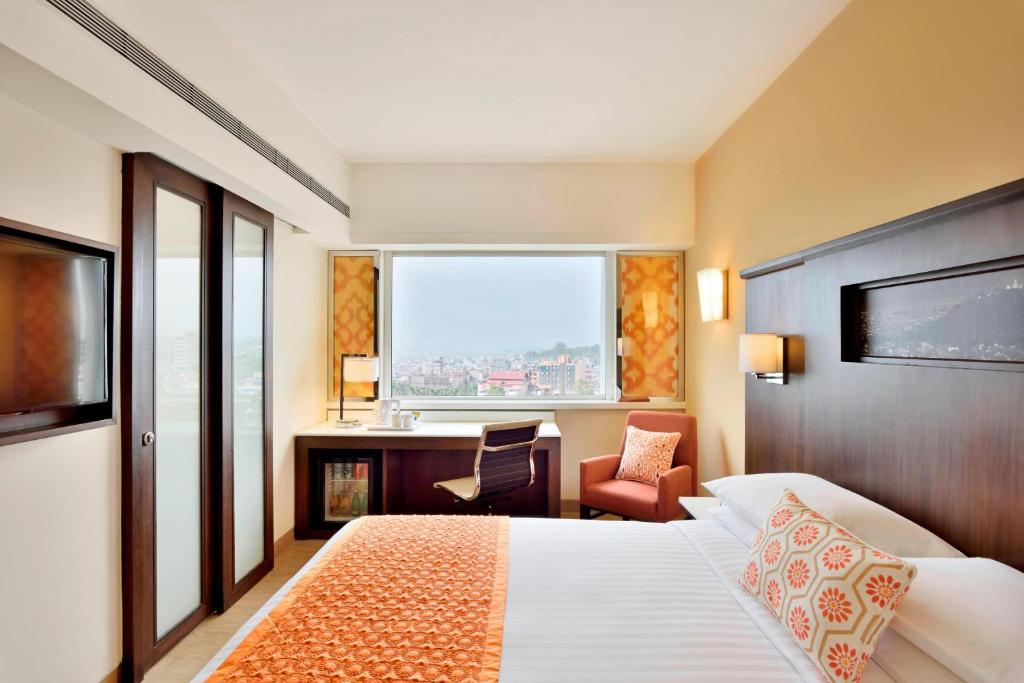 a hotel room with a bed and a desk and a window at Fairfield by Marriott Kathmandu in Kathmandu