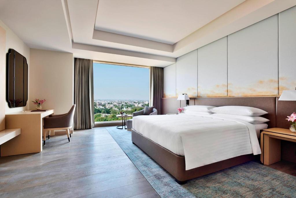 a hotel room with a large bed and a desk at Indore Marriott Hotel in Indore