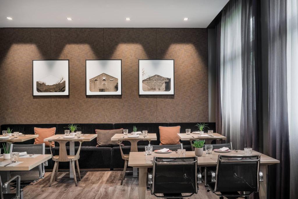 un restaurante con mesas, sillas y cuadros en la pared en AC Hotel Bologna by Marriott en Bolonia
