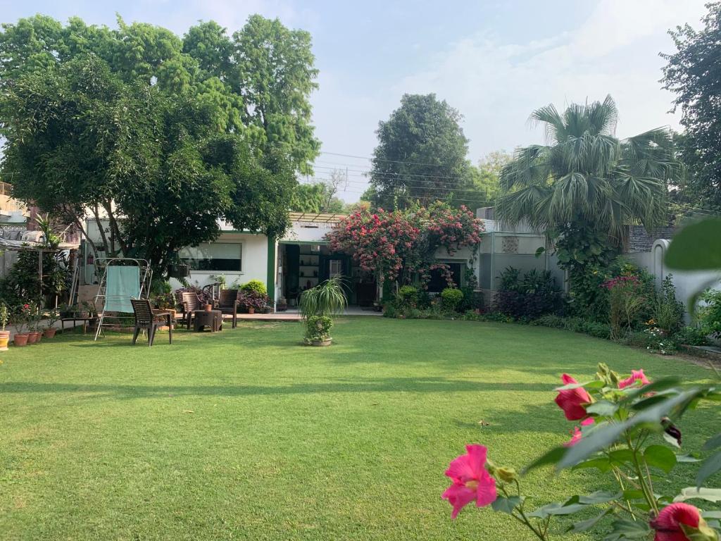 een tuin van een huis met een gazon met roze bloemen bij Green Serene Abode in Meerut