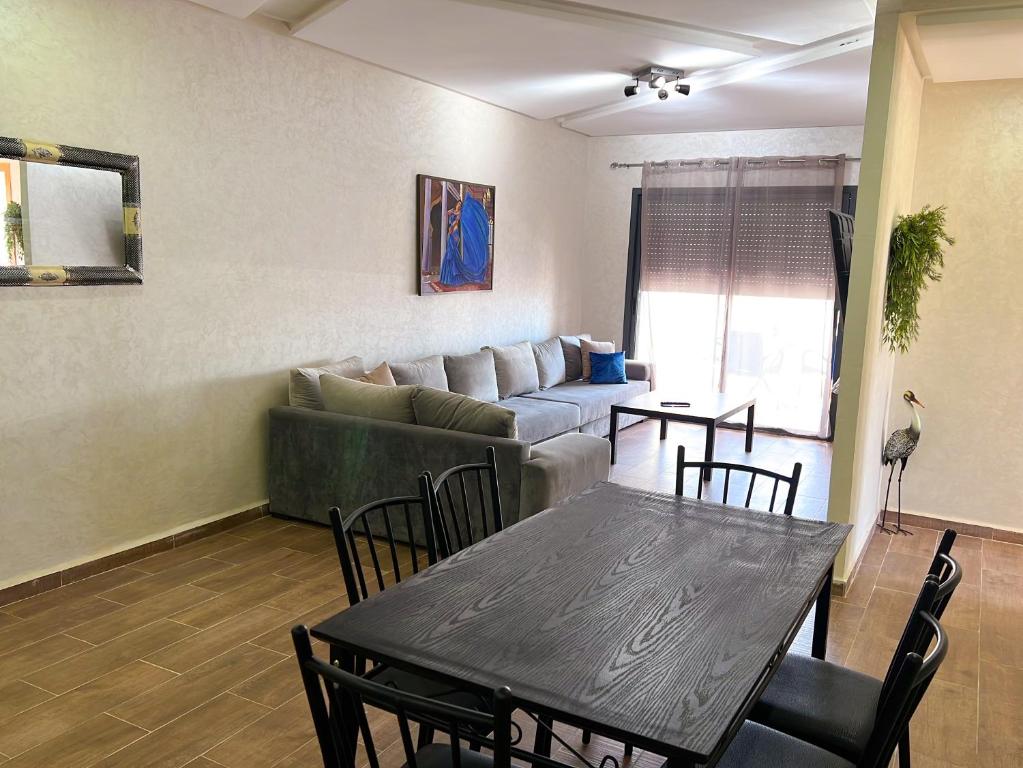 ein Wohnzimmer mit einem Tisch und einem Sofa in der Unterkunft Appartement Amwaj in Plage de Mehdia