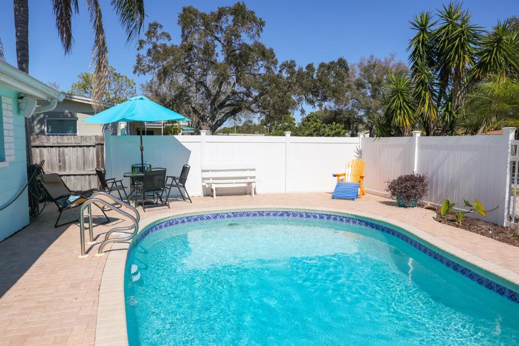 a swimming pool with a table and chairs and an umbrella at License to Chill - Heated Pool, Indian Rocks Beach, Play Room in Largo