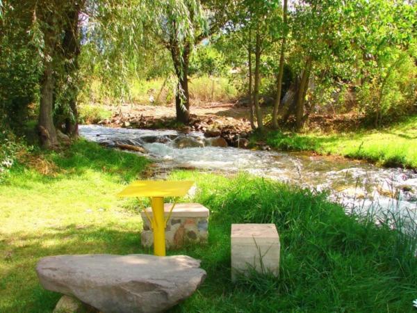 una mesa amarilla en la hierba junto a un río en Cabañas Pequeño Paraíso en Tunuyán