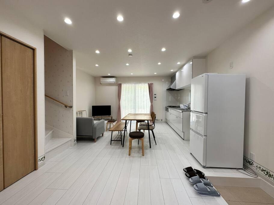 SHIRAHAMA condominium D-100 في Kanayama: مطبخ مع ثلاجة وطاولة وكراسي
