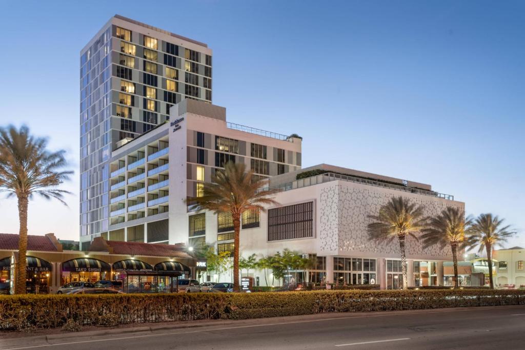 a tall building with palm trees in front of a street at Residence Inn Miami Sunny Isles Beach in Miami Beach