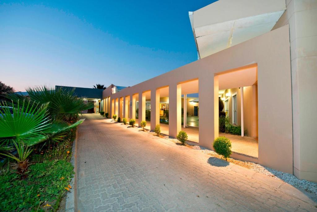 a building with a row of windows next to a sidewalk at Protea Hotel by Marriott Ondangwa in Ondangwa