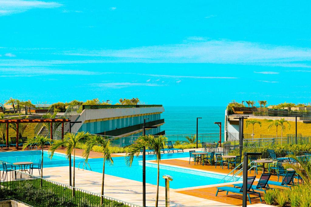 a swimming pool with palm trees and the ocean at Apartamento Resort em Praia grande - Ubatuba in Ubatuba