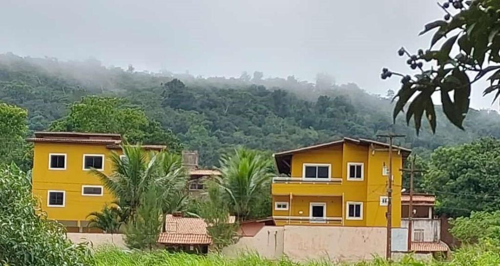 ein gelbes Haus mit einem Berg im Hintergrund in der Unterkunft Pousada Fernandes in Aratuba