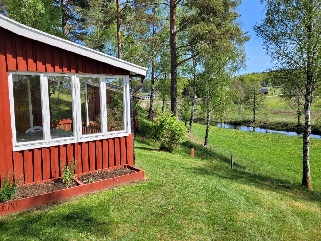 uma casa vermelha com vista para um rio em Sommarstuga em Vårgårda