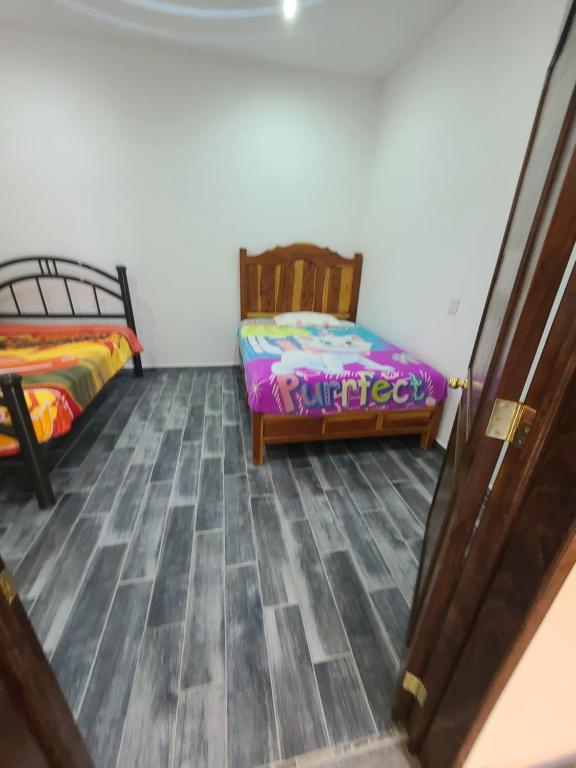 um quarto com 2 camas e piso em madeira em Departamentos Vista Nueva Malinalco em Malinalco