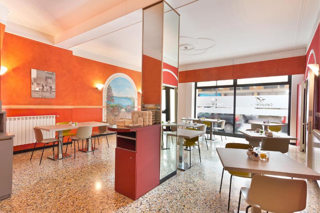 a restaurant with tables and chairs and windows at Hotel Calypso in Ventimiglia