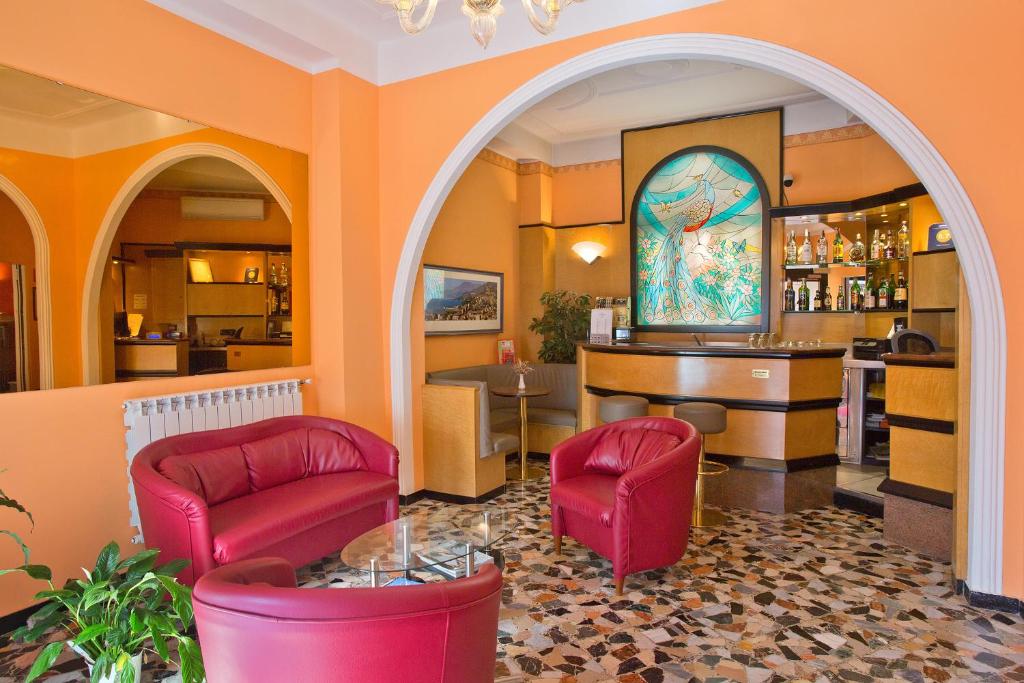 a lobby with two red chairs and a bar at Hotel Calypso in Ventimiglia