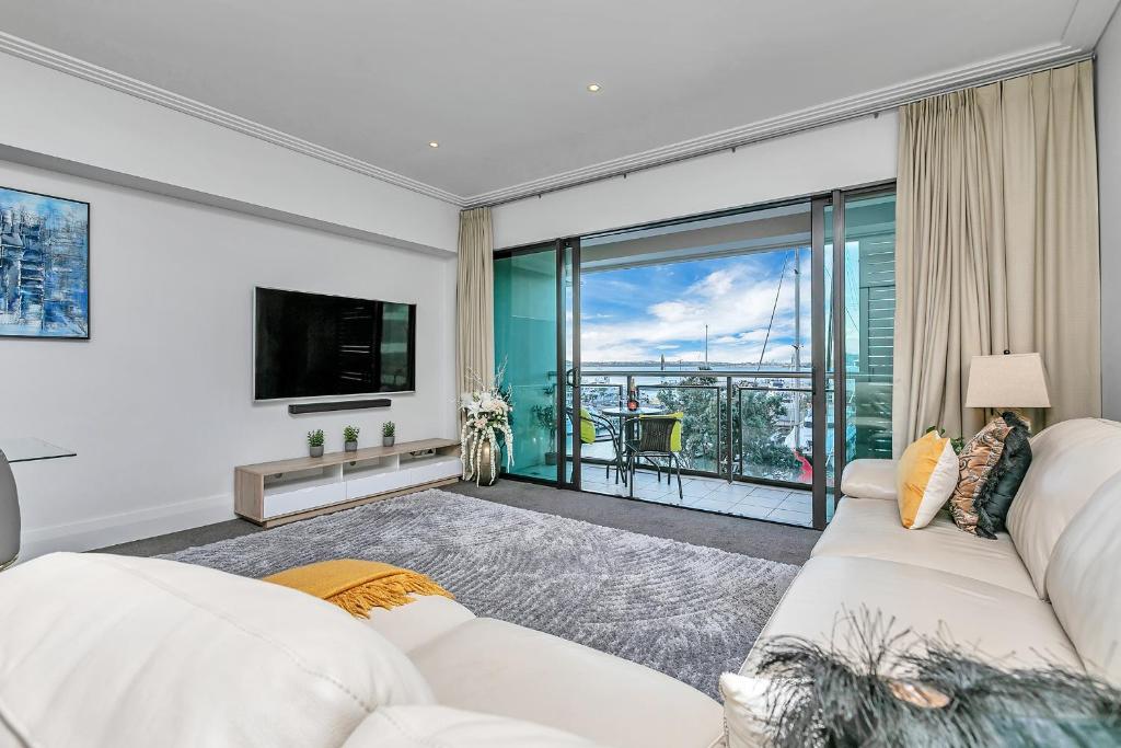 a living room with a white couch and a tv at Sunset Harbour Sanctuary + CP in Auckland