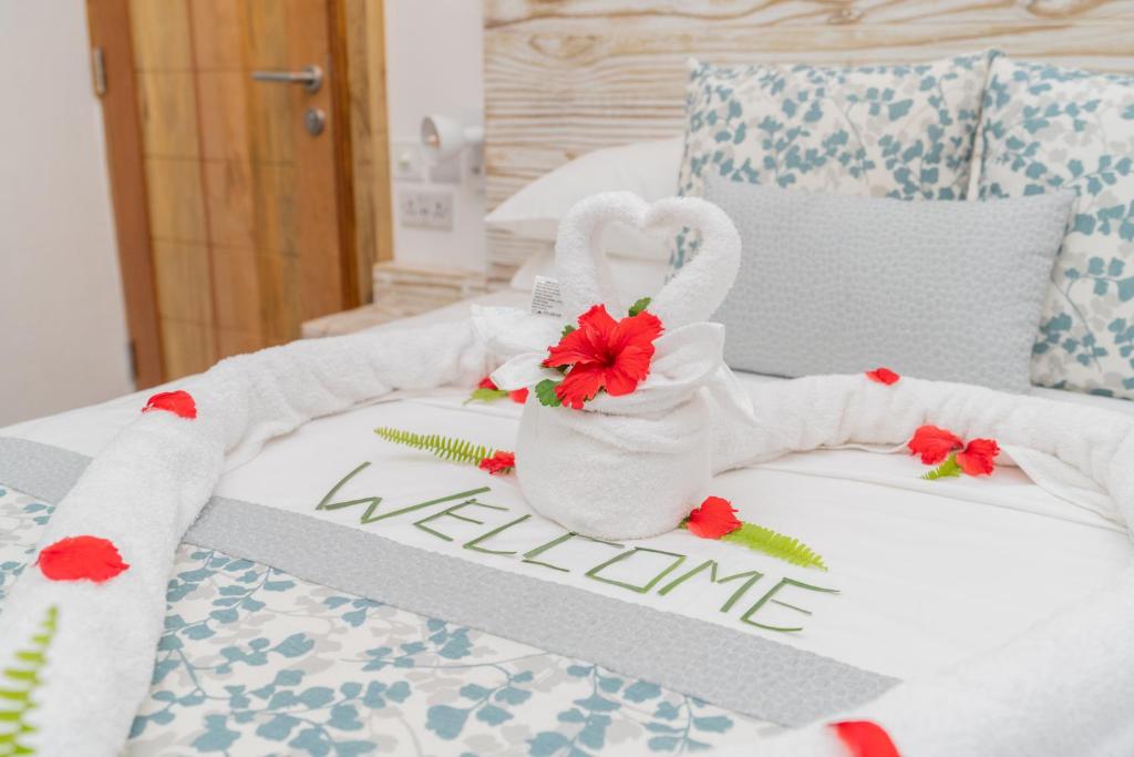 ein Bett mit einer weißen Decke mit Blumen drauf in der Unterkunft Romance Bungalows in Beau Vallon