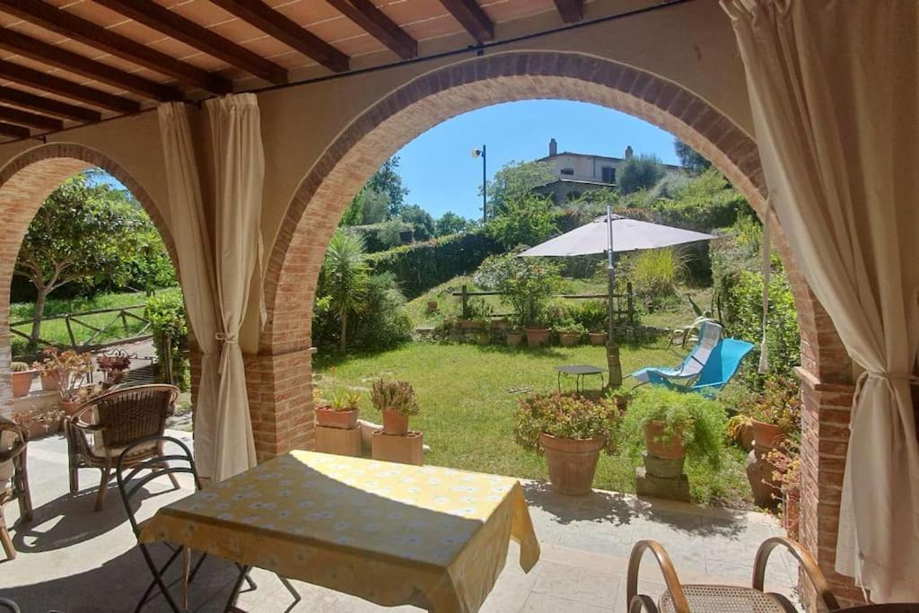 un patio al aire libre con un arco, una mesa y sillas en Residenza Anna, en Montemerano