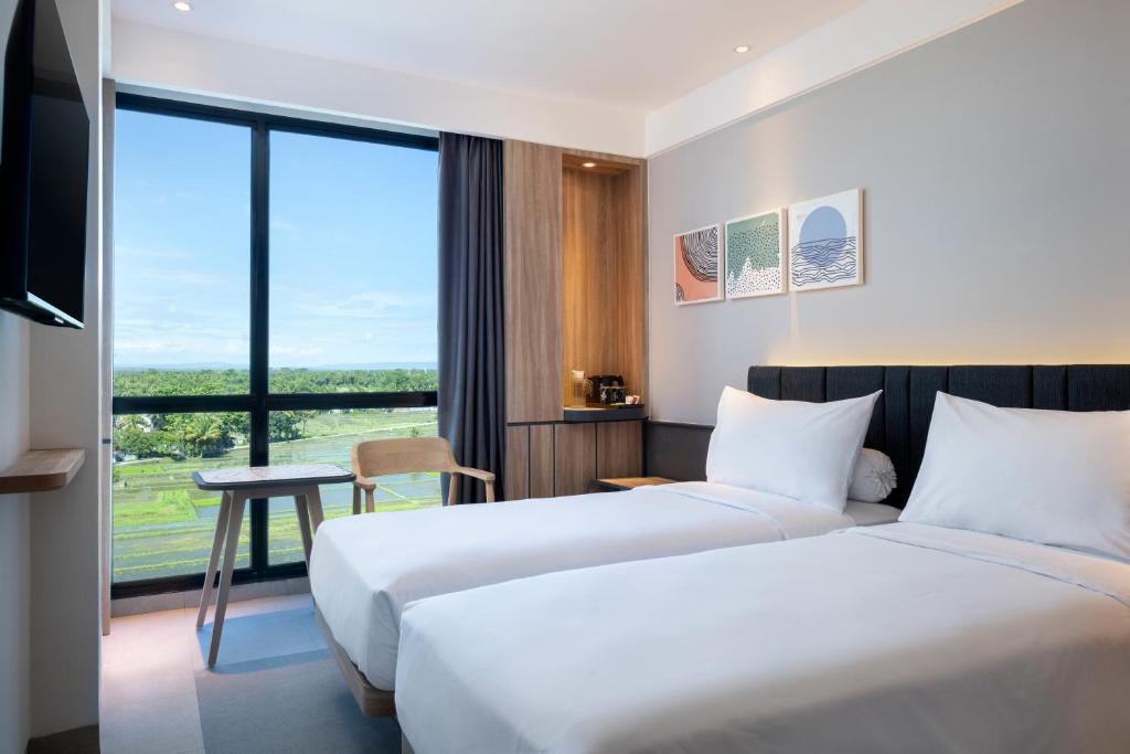 two beds in a hotel room with a view at ibis Yogyakarta International Airport Kulon Progo in Yogyakarta