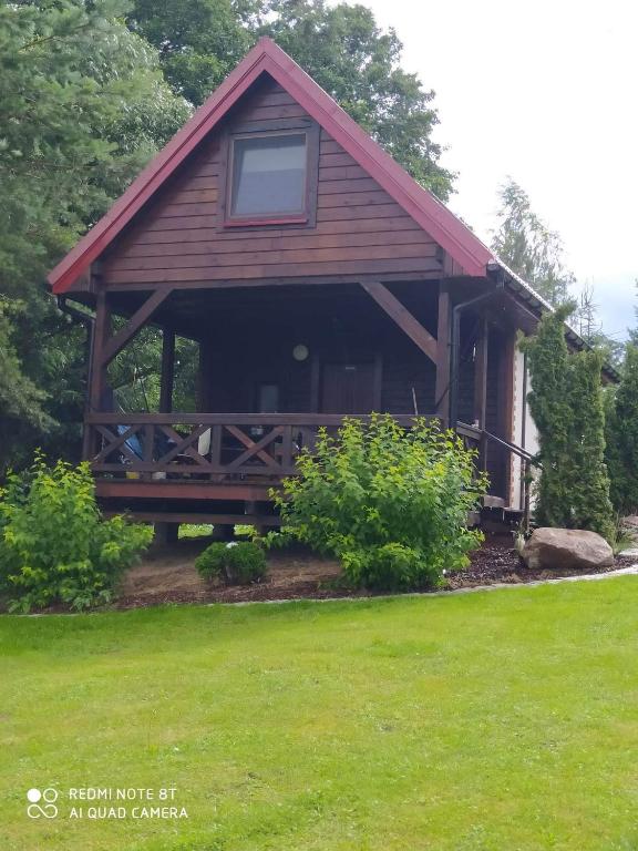 a log cabin with a porch and green grass at Agroturystyka Giże - domek letni in Ełk
