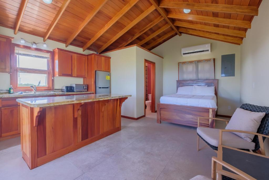 a kitchen with wooden cabinets and a bed in a room at The Cottages at Island Pearl Gold Standard Certified in Caye Caulker
