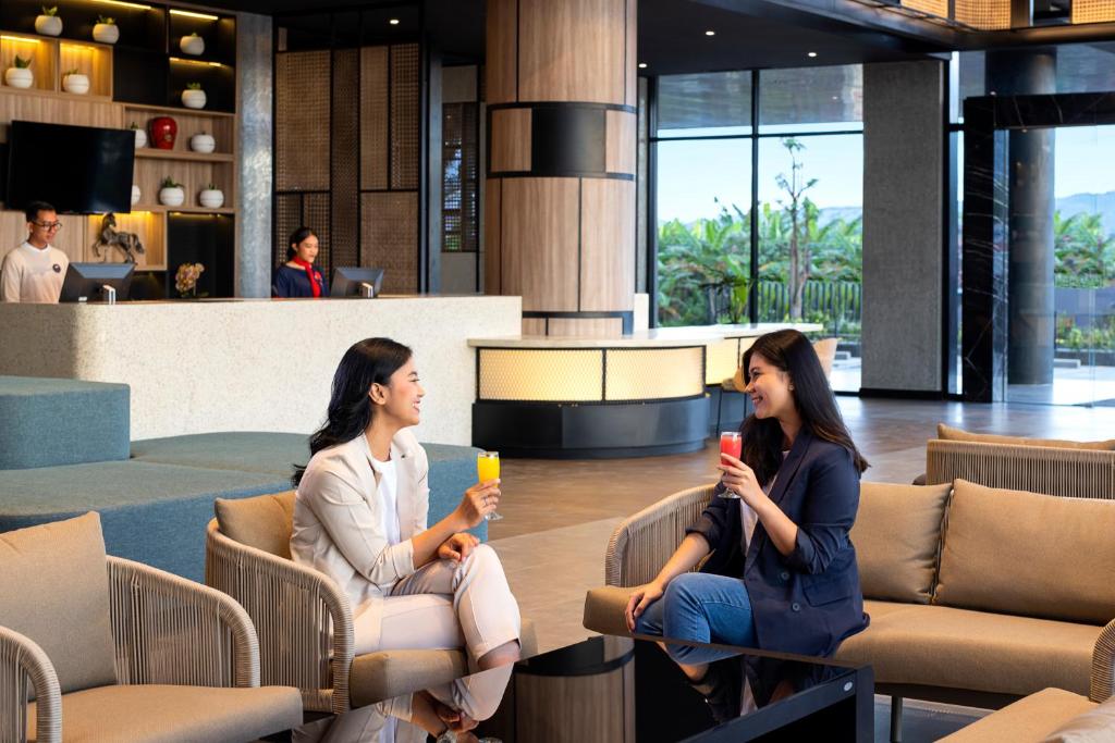 two women sitting in chairs in a lobby with drinks at ibis Yogyakarta International Airport Kulon Progo in Yogyakarta