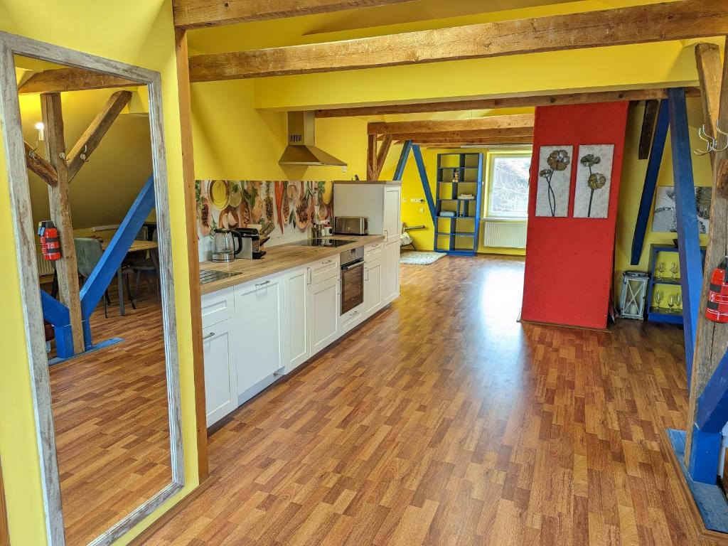 a large kitchen with wooden floors and yellow walls at Anton's bunte Welt (100 m², Parkplatz, Garten und viel mehr) in Albersdorf