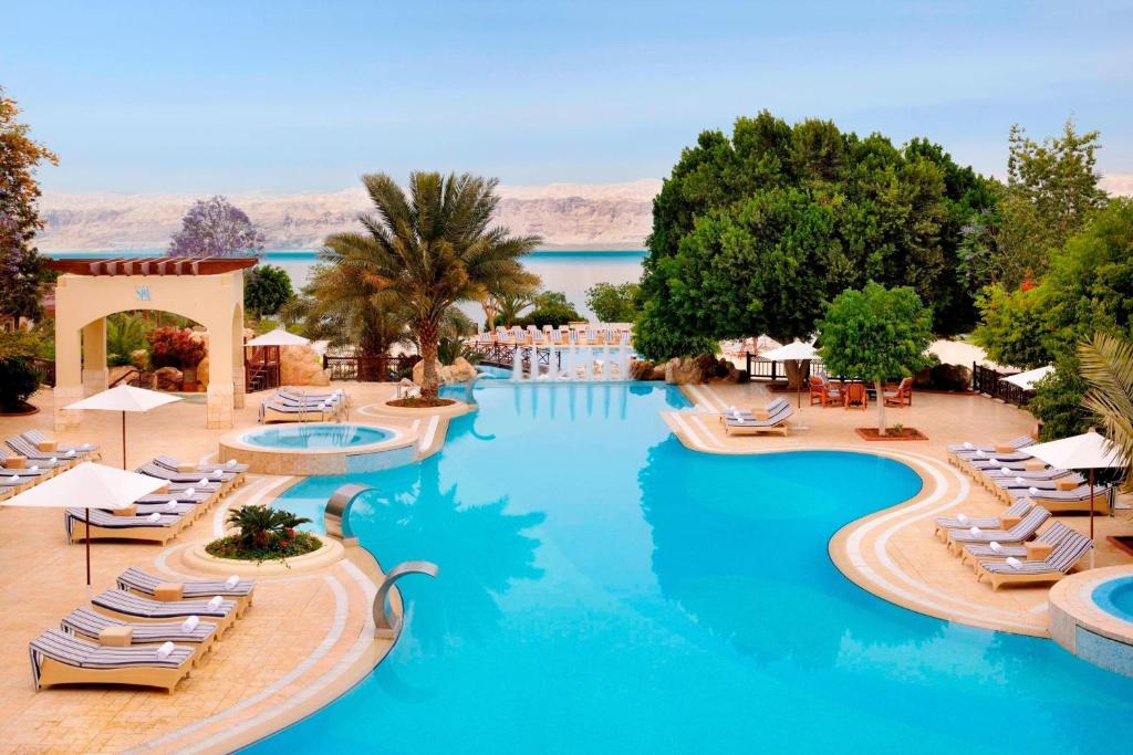 a resort with a pool with lounge chairs and water at Dead Sea Marriott Resort & Spa in Sowayma