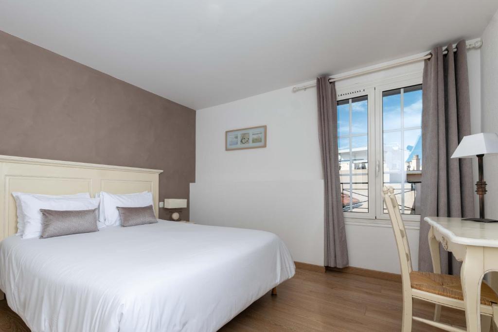 a bedroom with a bed and a desk and a window at Hôtel Beau Site - Cap d'Antibes in Antibes