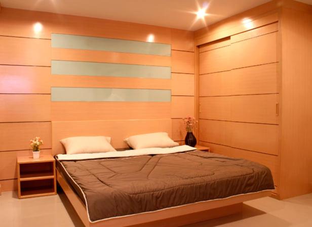 a bedroom with a bed with wooden walls at Love mansion in Bangkok