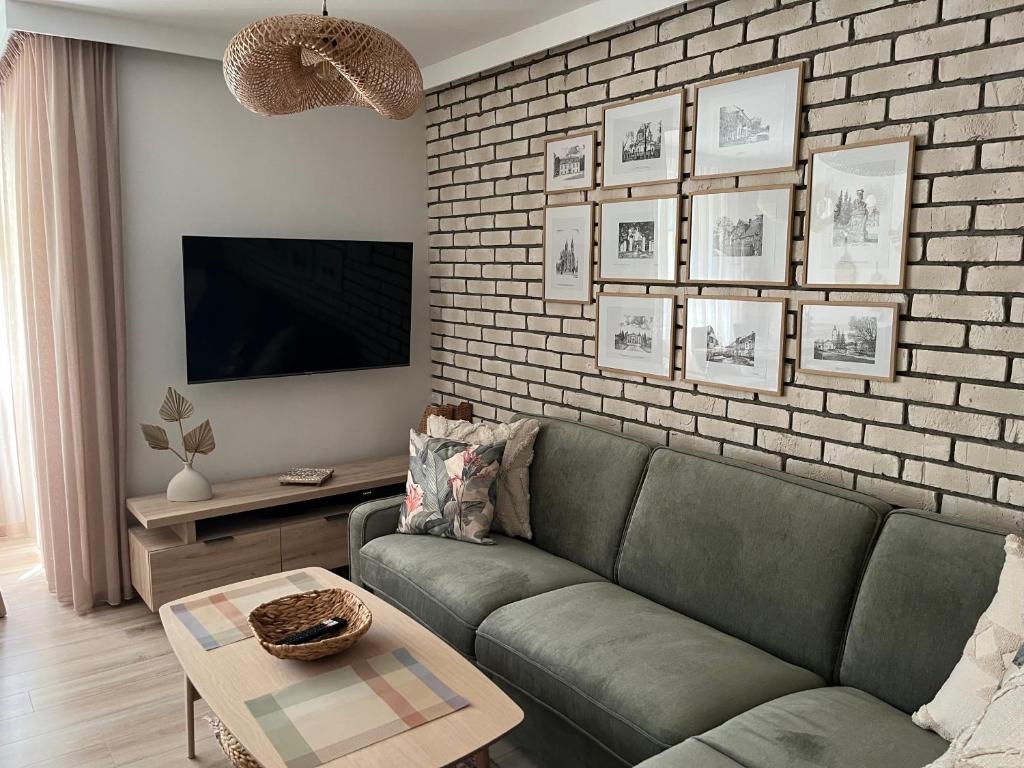 a living room with a green couch and a brick wall at Apartament Akademicka in Białystok