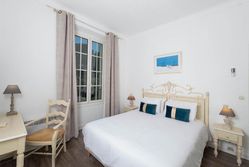 a bedroom with a white bed and a desk and a chair at Hôtel Beau Site - Cap d'Antibes in Antibes