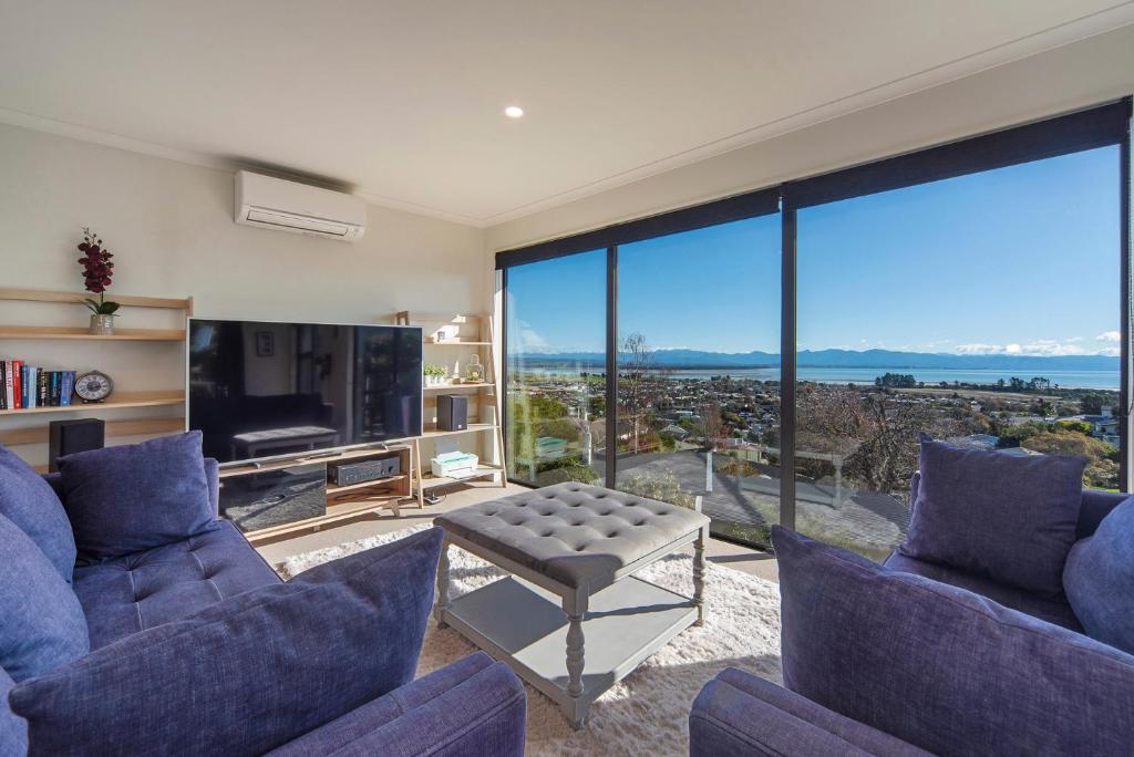 a living room with purple furniture and a large window at Blue Water Views in Nelson