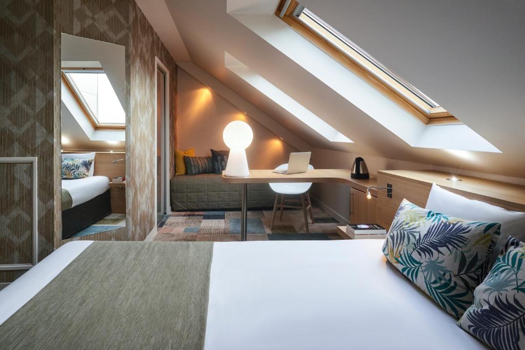 a bedroom with a bed and a desk in a room at Kyriad Le Mans Est in Le Mans