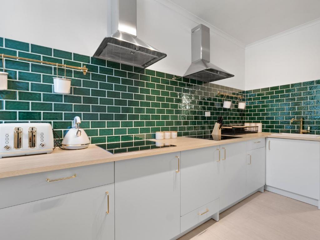 una cocina con armarios blancos y azulejos verdes de metro en VENUS Central Sydney - FEMALE ONLY HOSTEL en Sídney