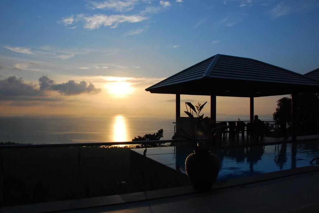 una puesta de sol sobre una piscina con un protector solar en El Cid Villa en Nathon