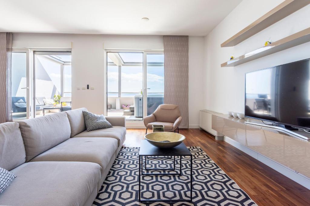 a living room with a couch and a tv at Apartments Blue Maris Žnjan in Split