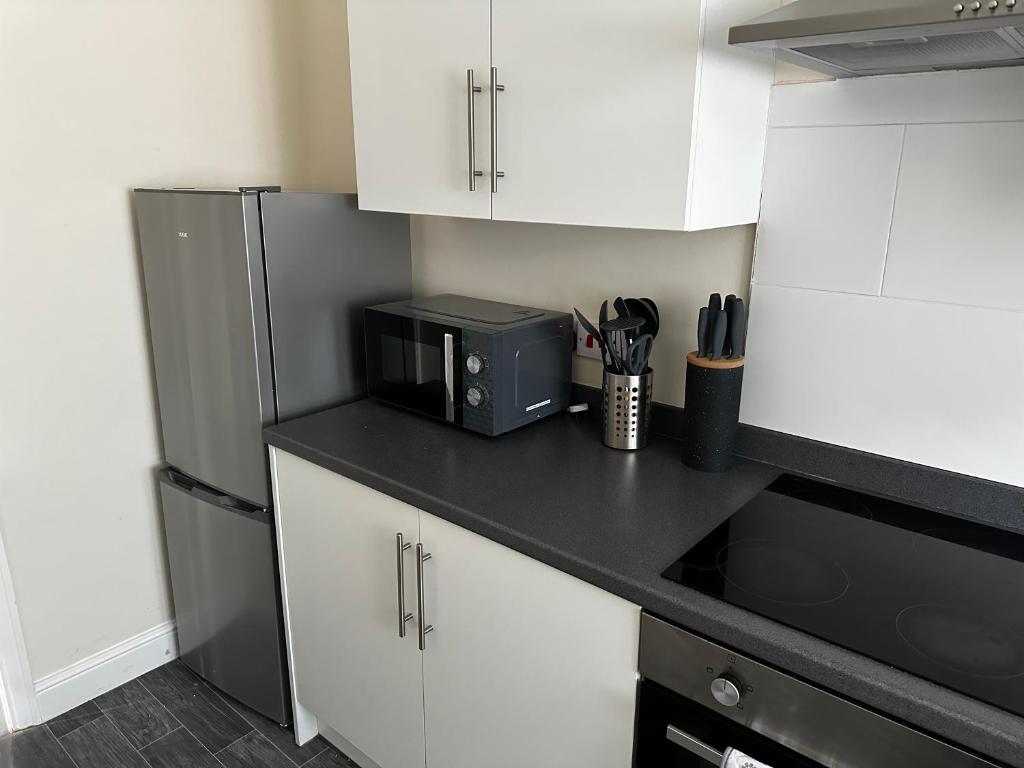 a kitchen with a black microwave and a refrigerator at Safari Avenue one Bedroom Apartment in Stapleford
