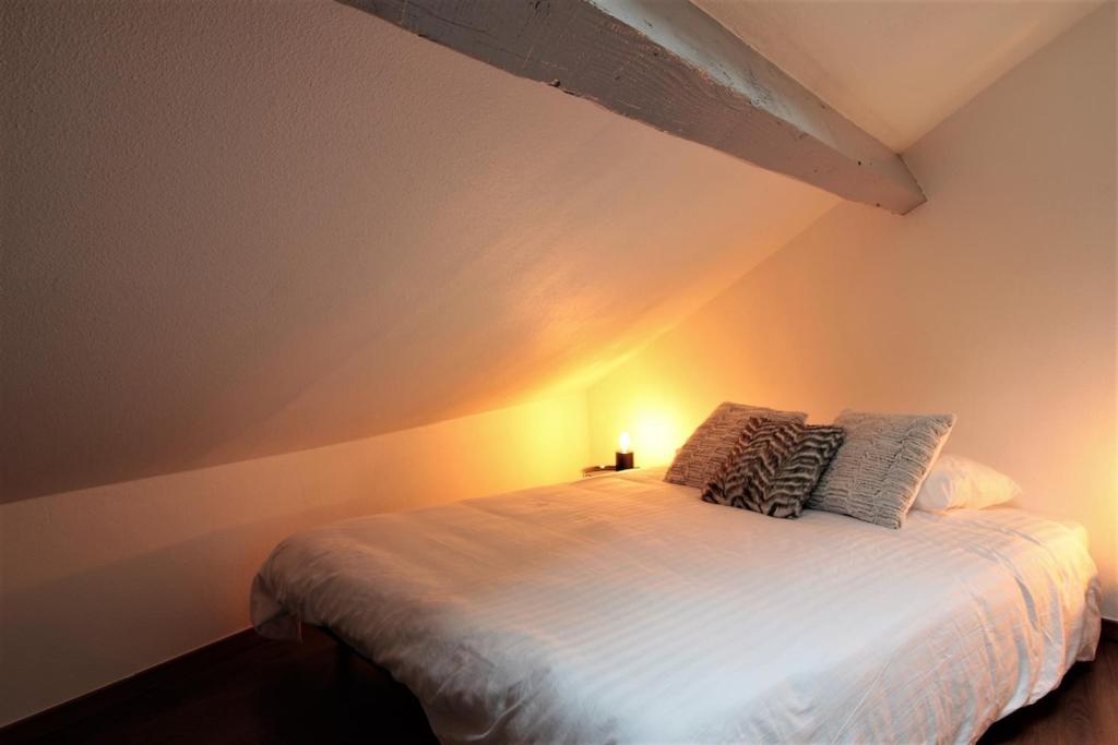 - une chambre avec un lit blanc éclairé dans l'établissement Grenier du Lac 100 m du lac, à Annecy