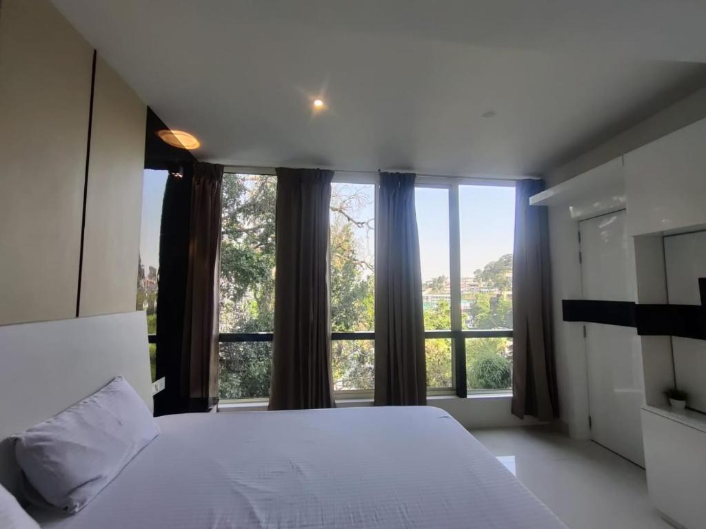 a bedroom with a white bed and a large window at The White House in Nainital