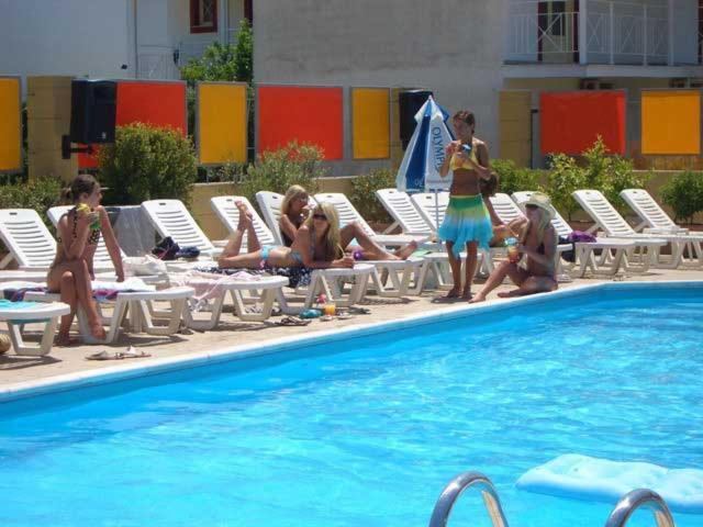 a group of people sitting on chairs near a swimming pool at Kavos Central in Kavos