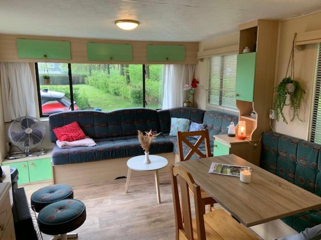 ein Wohnzimmer mit einem blauen Sofa und einem Tisch in der Unterkunft Stacaravan huren in het hart van bosrijk Drenthe op Recreatiepark De Tien Heugten in Schoonloo