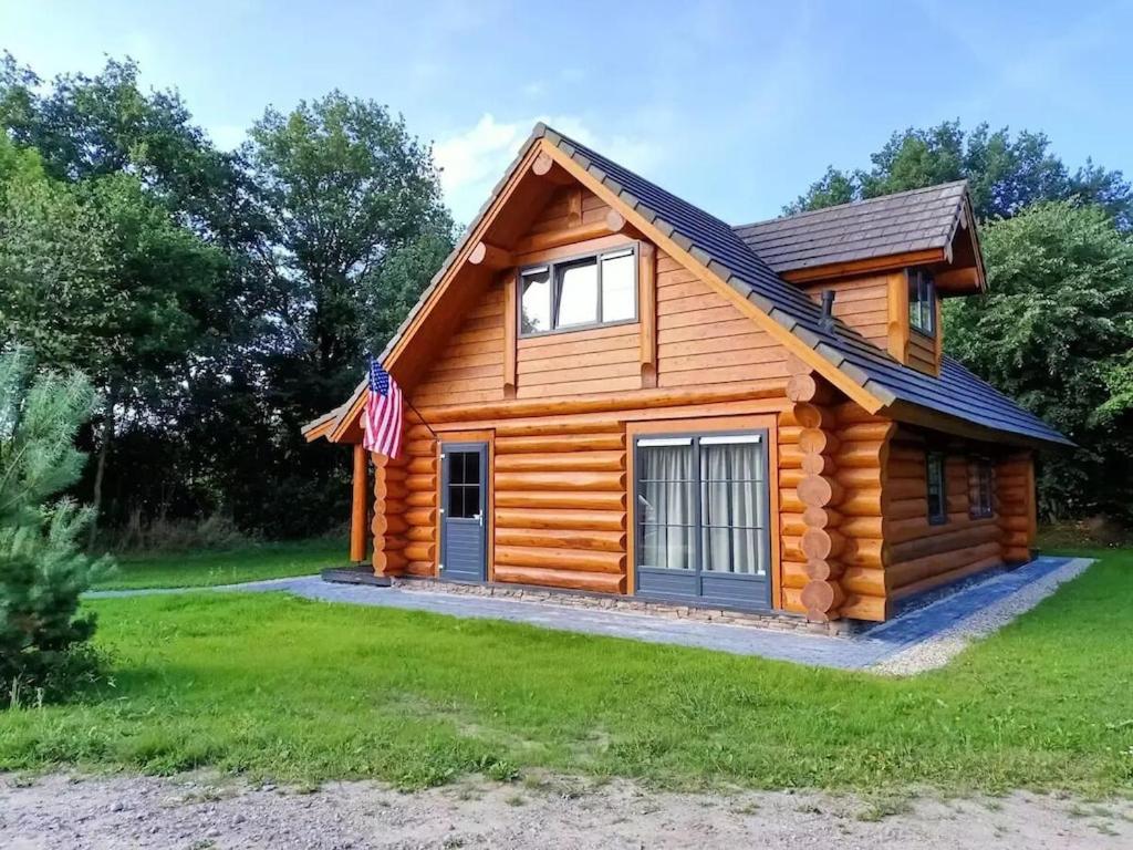 een blokhut met een vlag ervoor bij Unieke houten villa met SAUNA in Twente - 5p in Den Ham