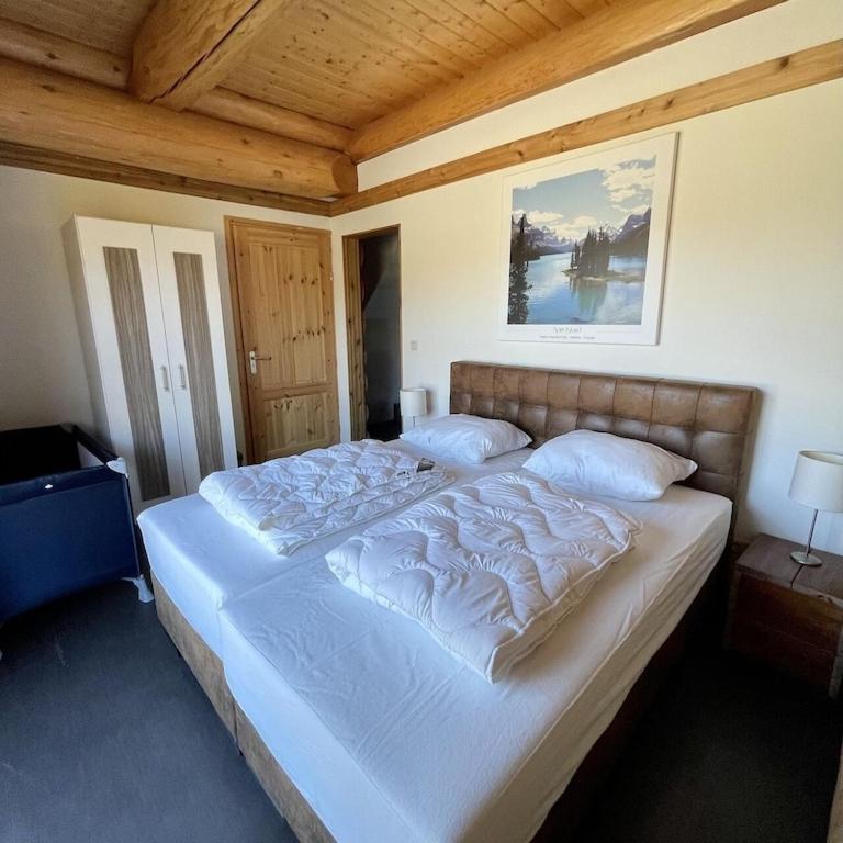 een groot wit bed in een slaapkamer met een houten plafond bij Unieke houten villa met SAUNA in Twente - 5p in Den Ham