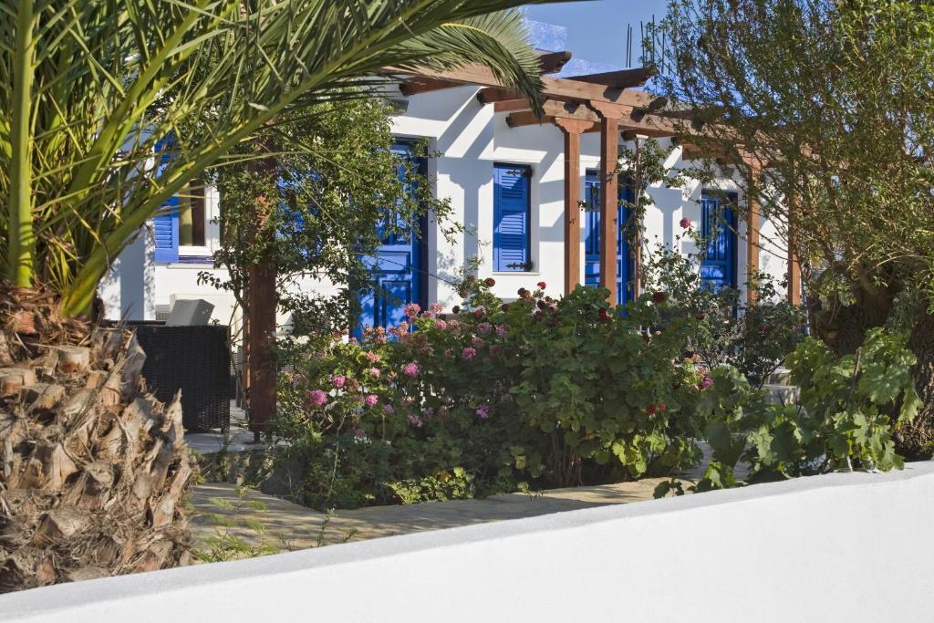 a white house with blue windows and flowers at Studio Filoxenia in Lipsoi