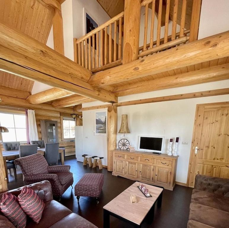 een woonkamer met houten plafonds en een woonkamer met een bank bij Unieke houten villa met SAUNA in Twente - 5p in Den Ham
