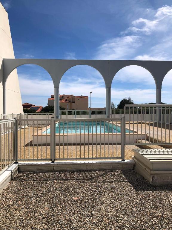 une clôture avec des arches devant une piscine dans l'établissement Appartement en résidence, au Barcarès
