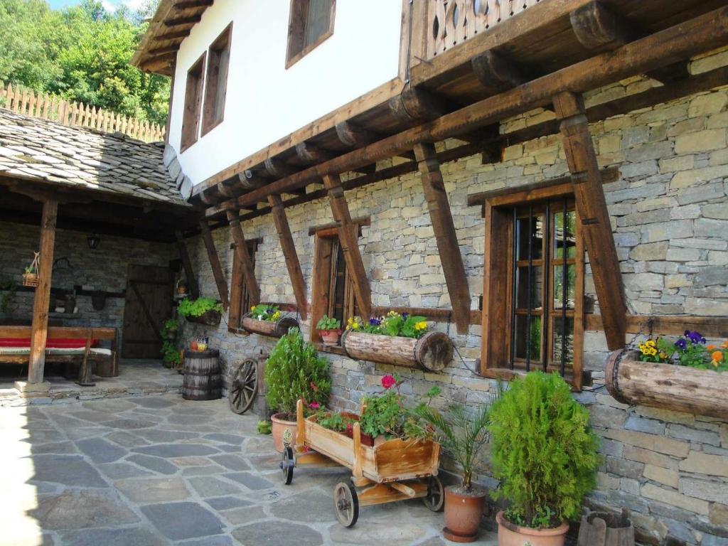 una casa in pietra con piante in vaso sul lato di Leshten Valentin's House a Leshten