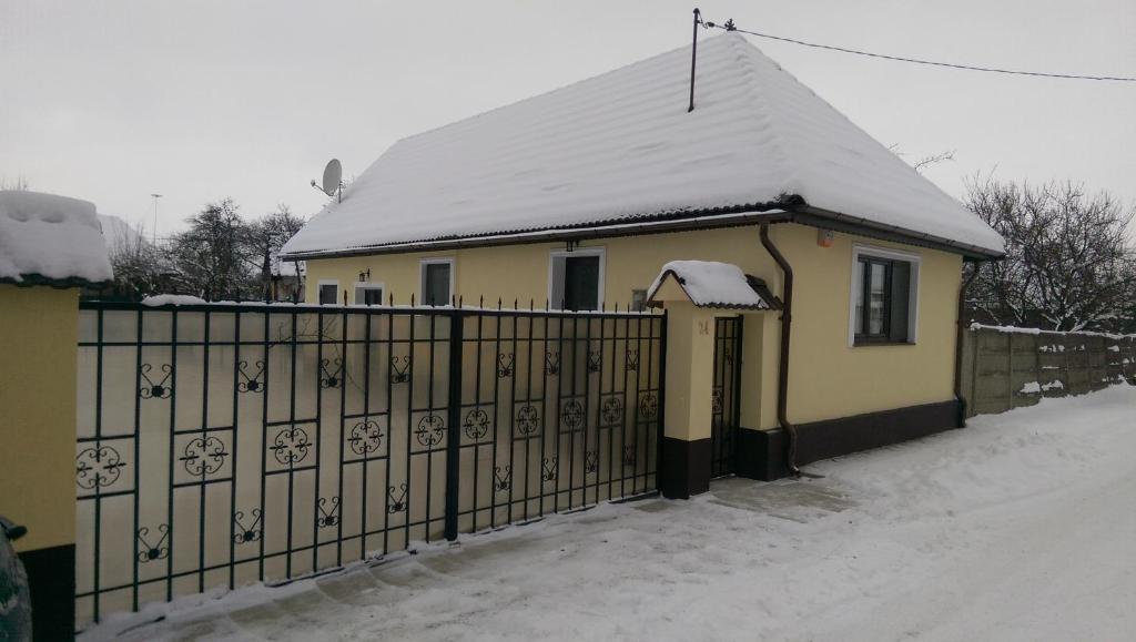 a house with a fence and a snow covered roof at Eva's Little House - Acasă la Tăticul Albinelor in Şinca Veche