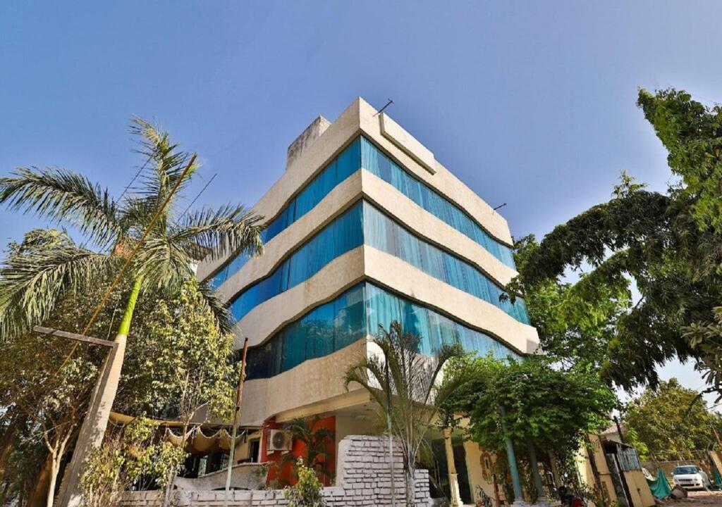 a tall building with palm trees in front of it at The Sky Imperial Hotel Yahvi in Vadodara