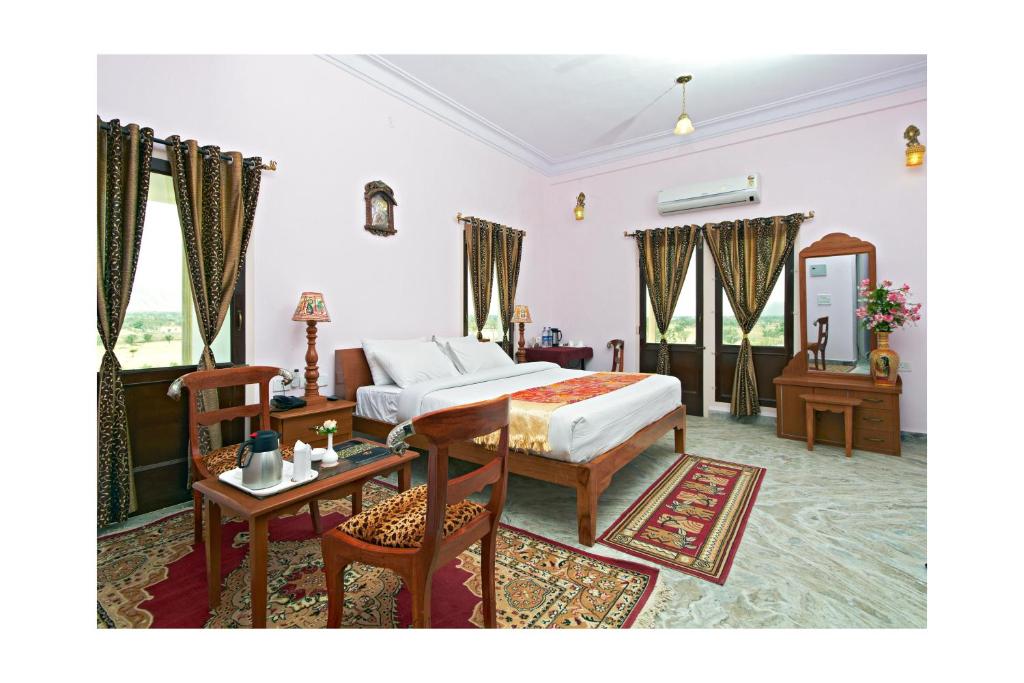 1 dormitorio con 1 cama, mesa y sillas en Satyam Palace Resort, en Pushkar